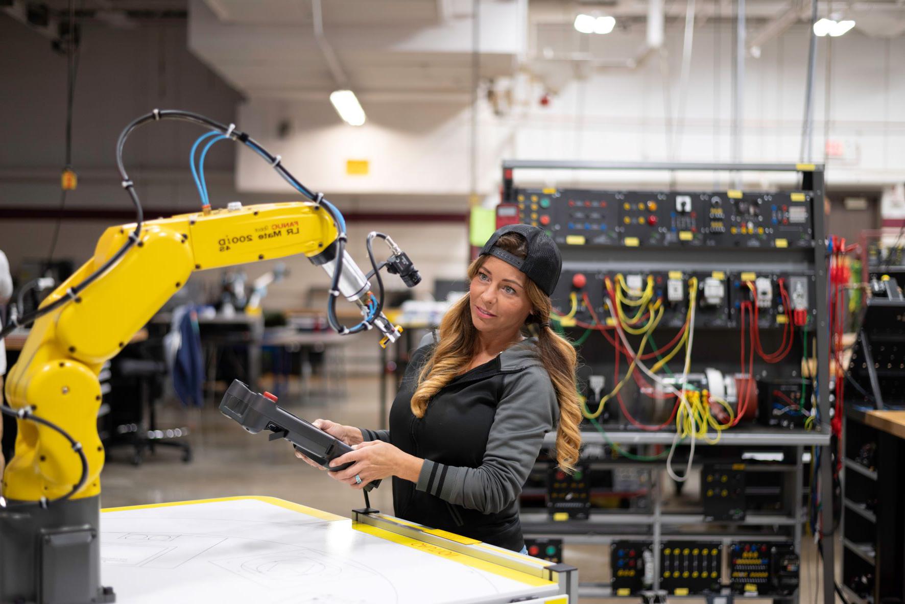 机器人学的女学生用遥控器和机械臂工作